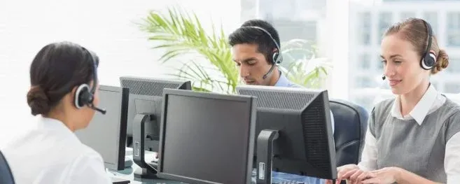 Customer Support Team Working at Desktop Computers with Headsets