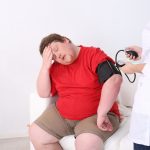 Doctor examining patient obesity on light background