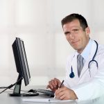 Closeup of doctor at his desk in front of computer